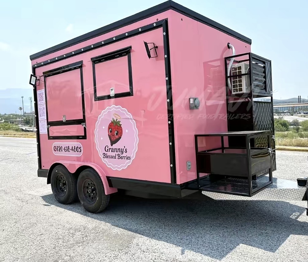 Pink berry stand trailer with logo and contact number, parked outdoors on a sunny day.