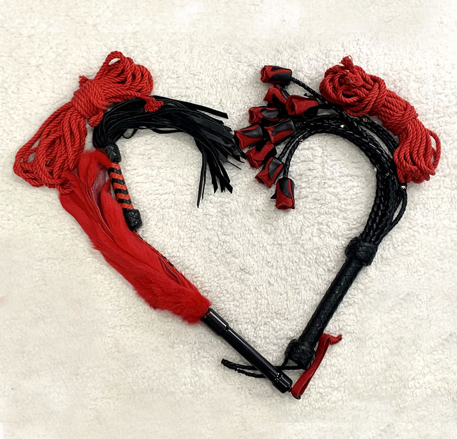 Two horse bridles with red and black decorative elements arranged to form a heart shape on a light surface.