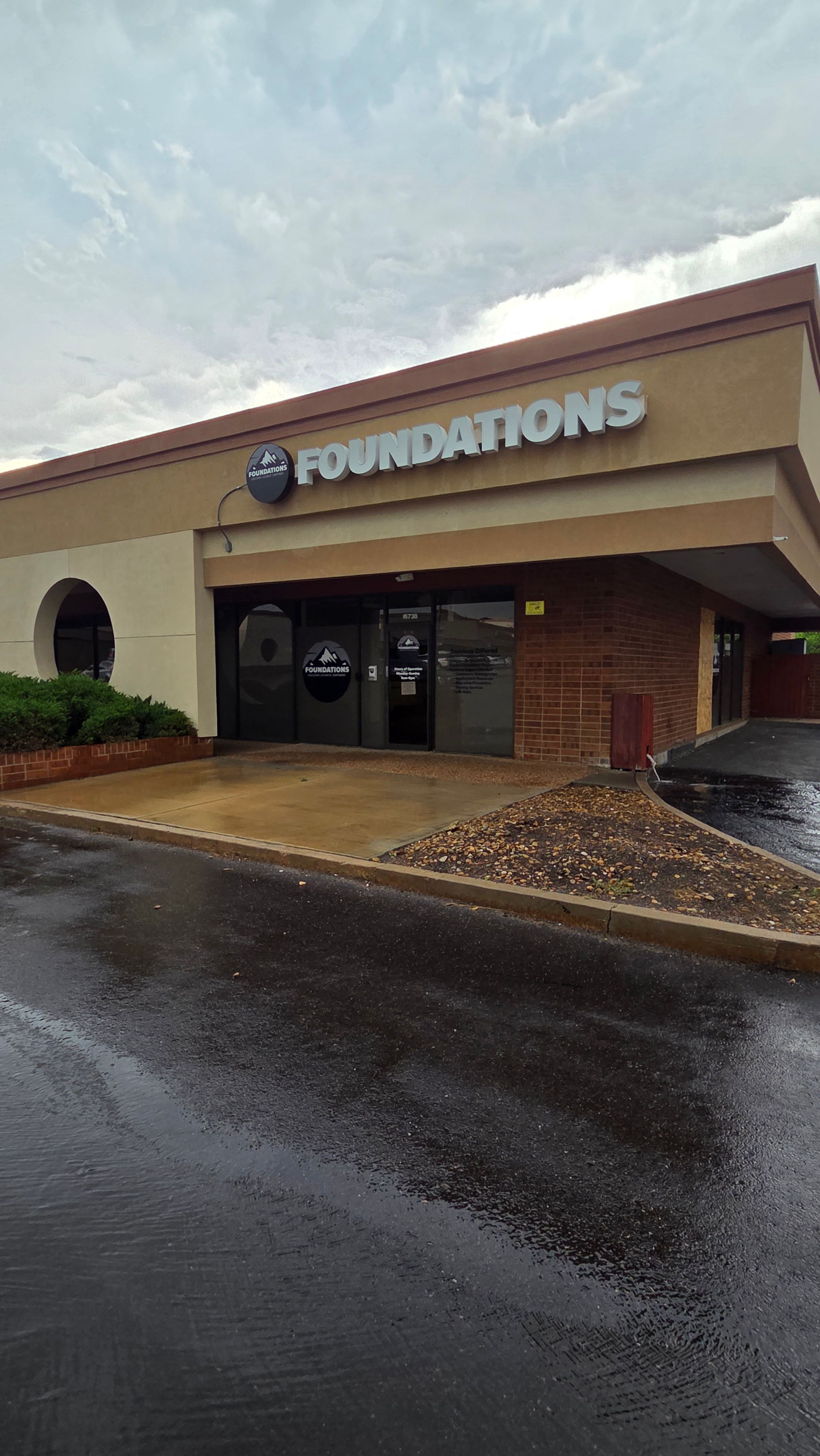 Building with a sign that reads 'AQUARIUM' and a display window, with a wet parking lot in front.