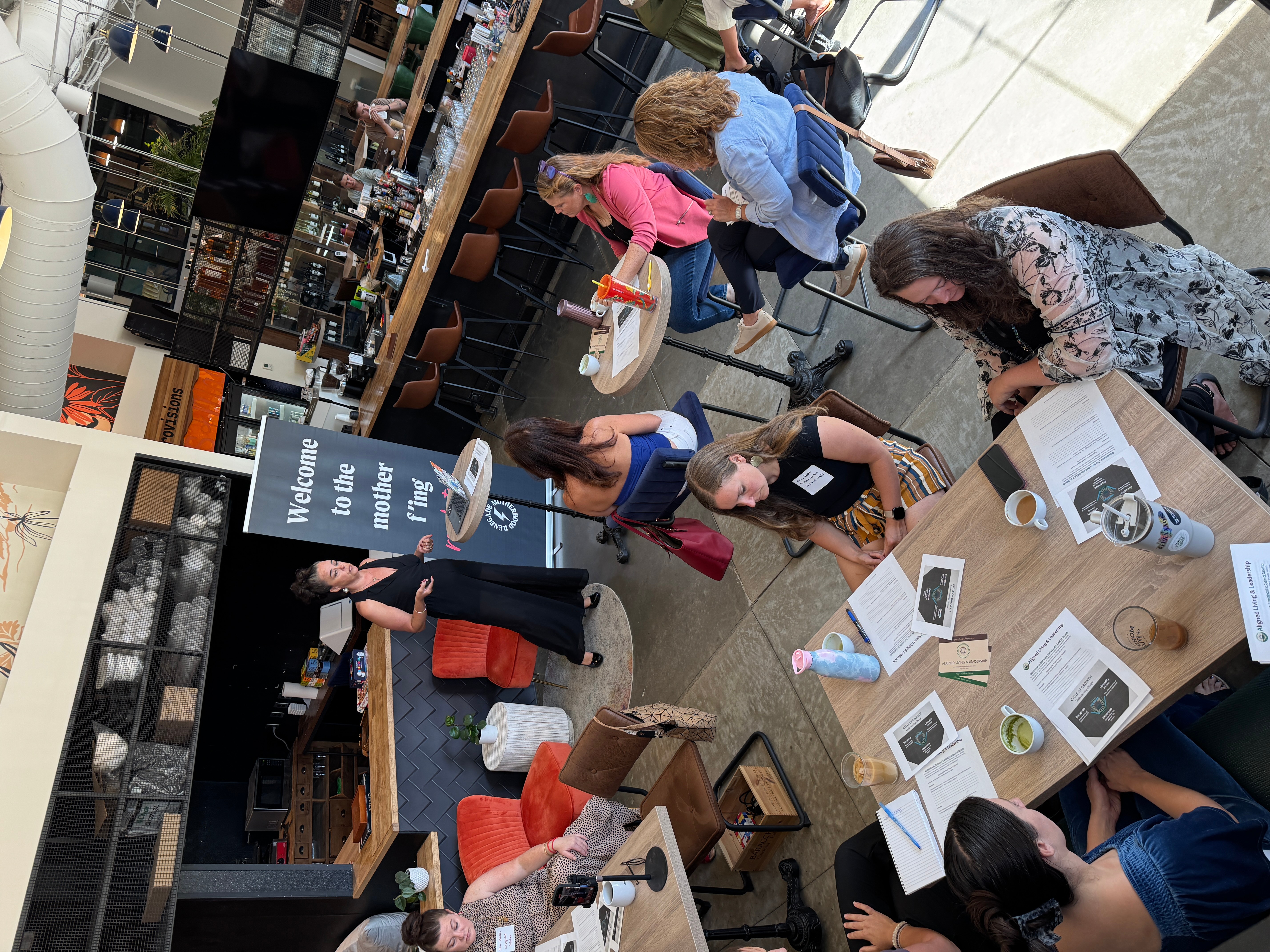 People browsing books and magazines at a bookstore or library, with tables and shelves filled with reading materials.