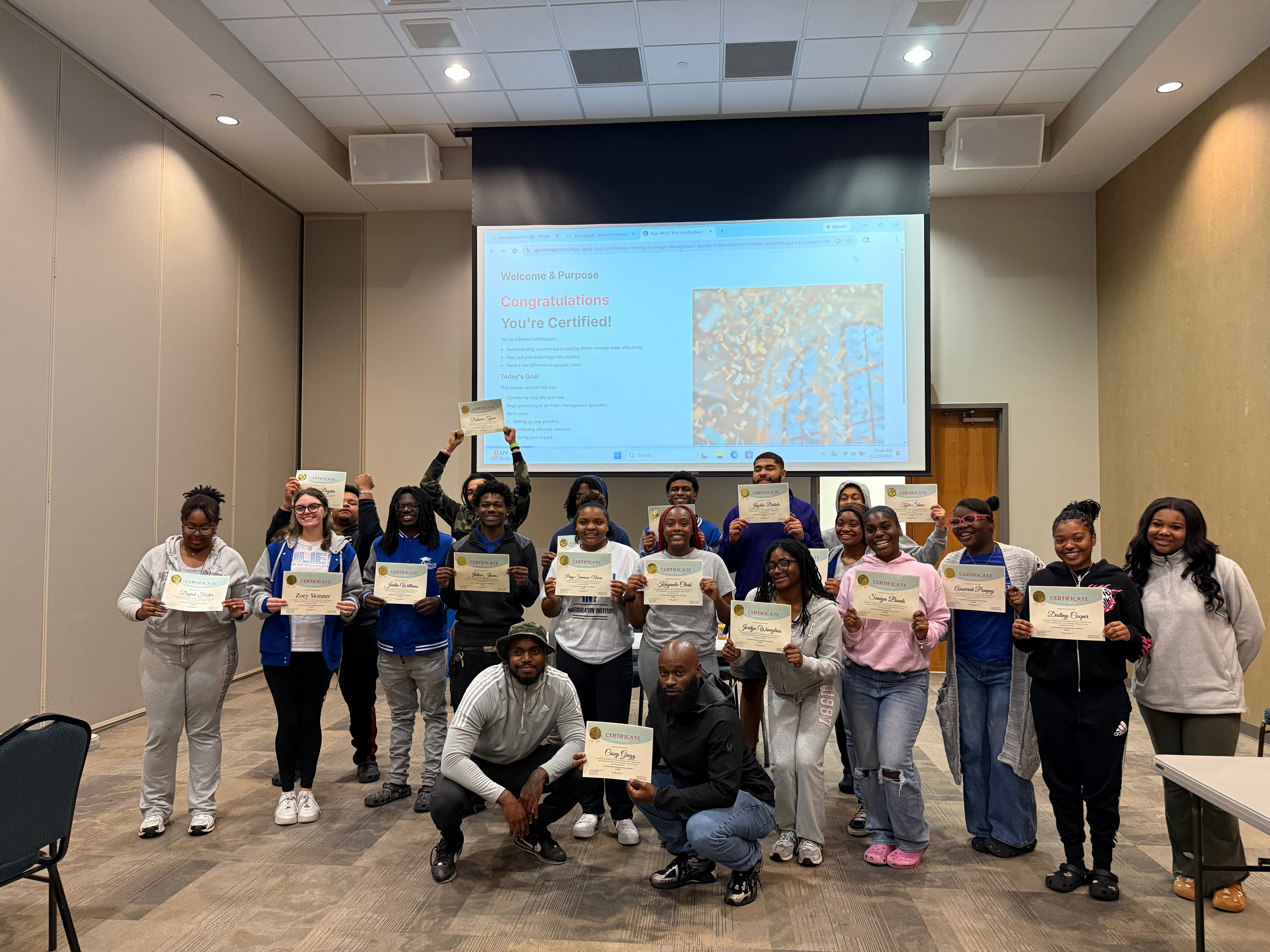 Group of people holding certificates in a conference room with a large screen displaying a map behind them.